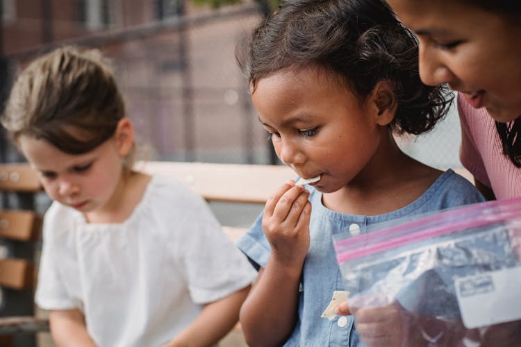 Little Girls Eating Snacks Outdoors 