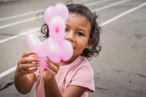 A Girl Wearing Pink Shirt Holding a Baloon
