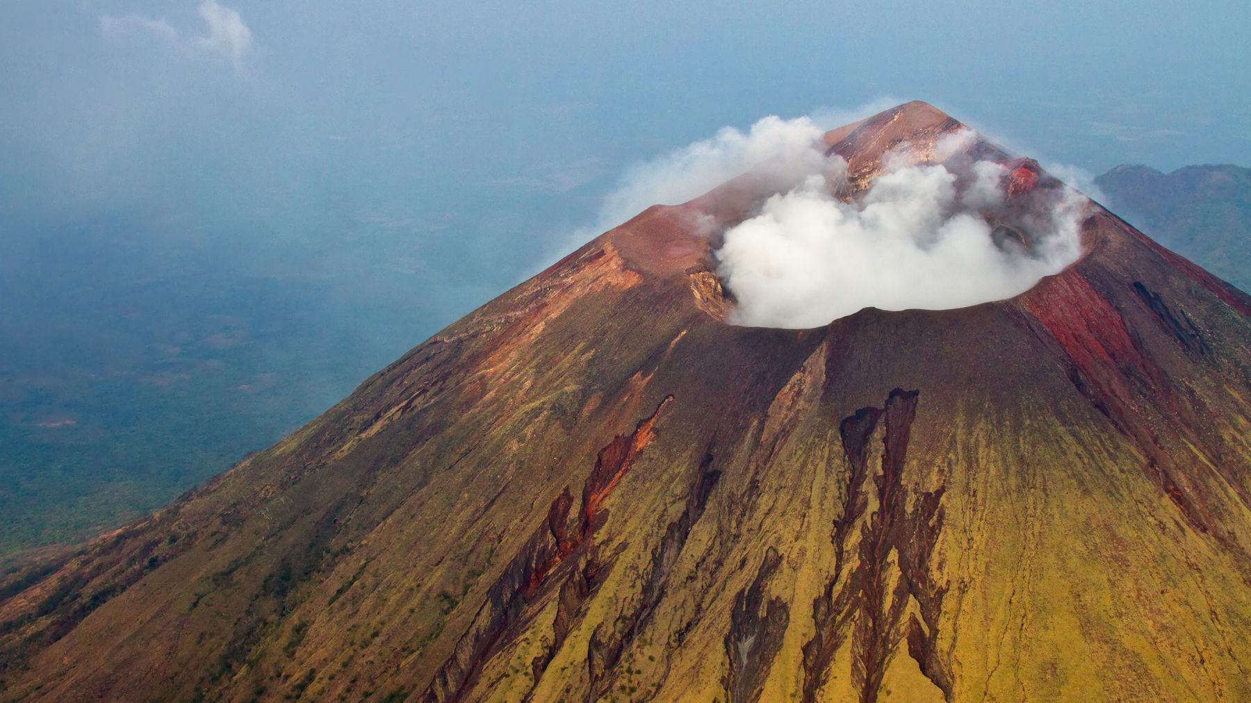 Stunning aerial view of San Cristobal Volcano in Nicaragua with smoke and steam rising from the crater.