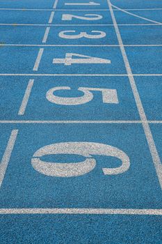 Close-up view of an empty blue athletic track featuring starting lane numbers.