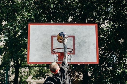 A man jumps to dunk a basketball outdoors, displaying athletic energy and skill.