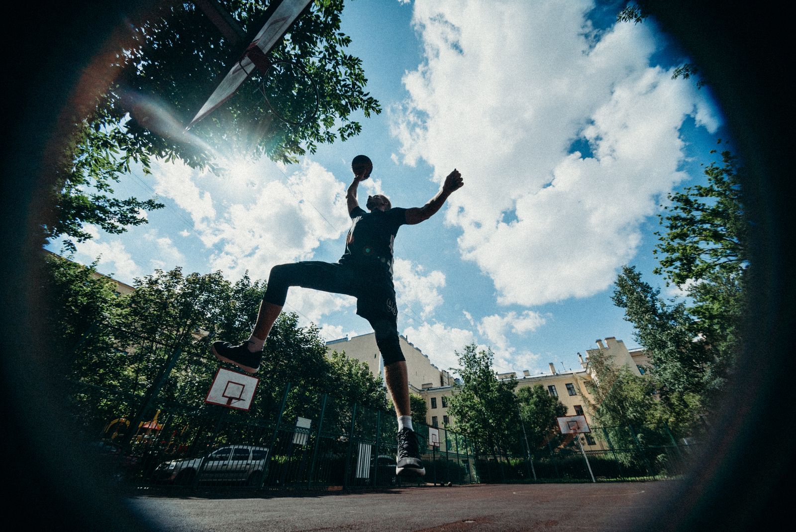 Silhueta de jogador de basquete em salto para arremesso contra o céu aberto