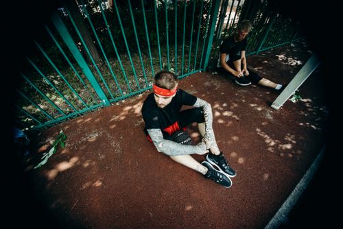 Free Two men sitting on a playground with sportswear, resting after an outdoor workout. Stock Photo