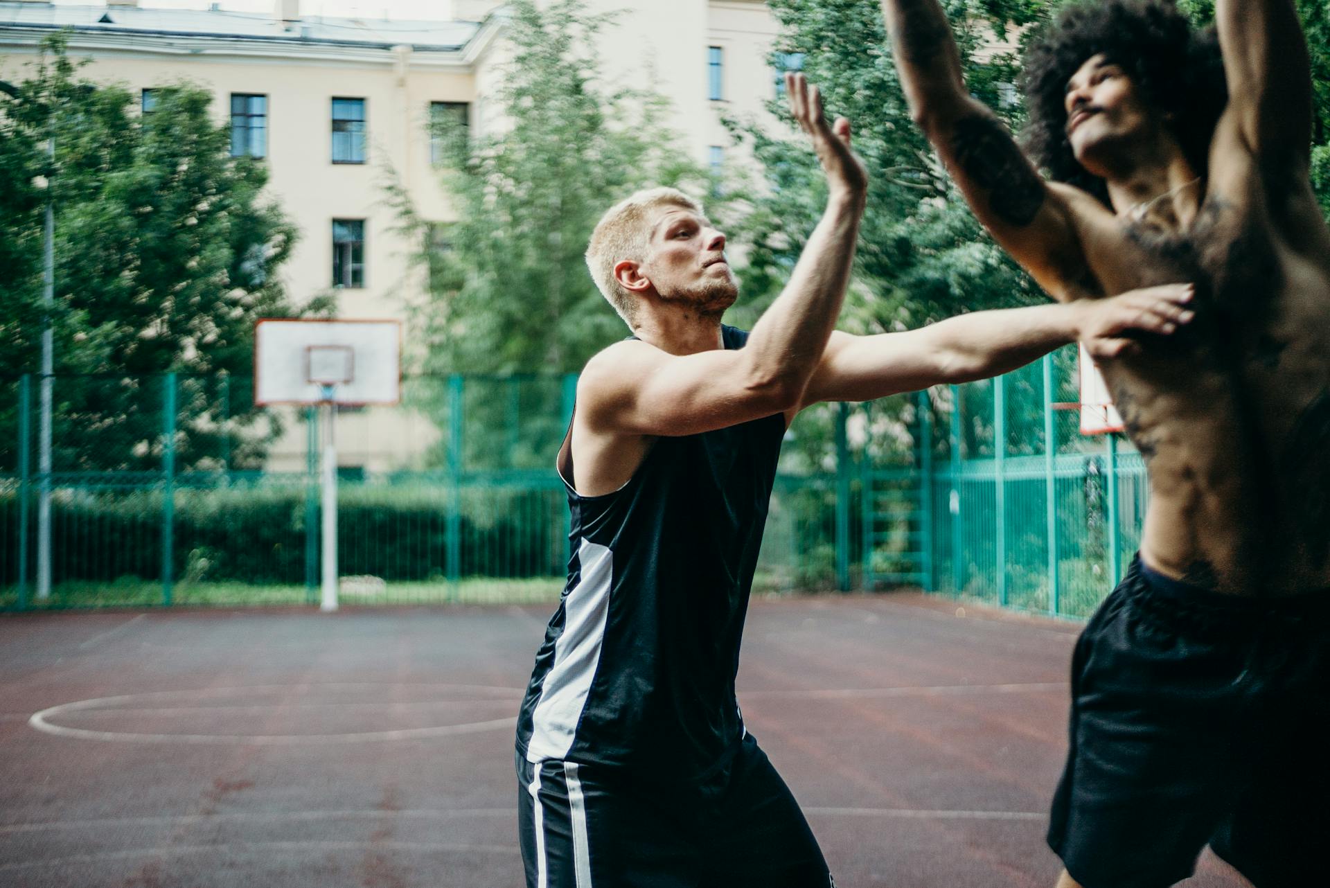 Two men playing competitive basketball on an outdoor court, showcasing action and intensity.