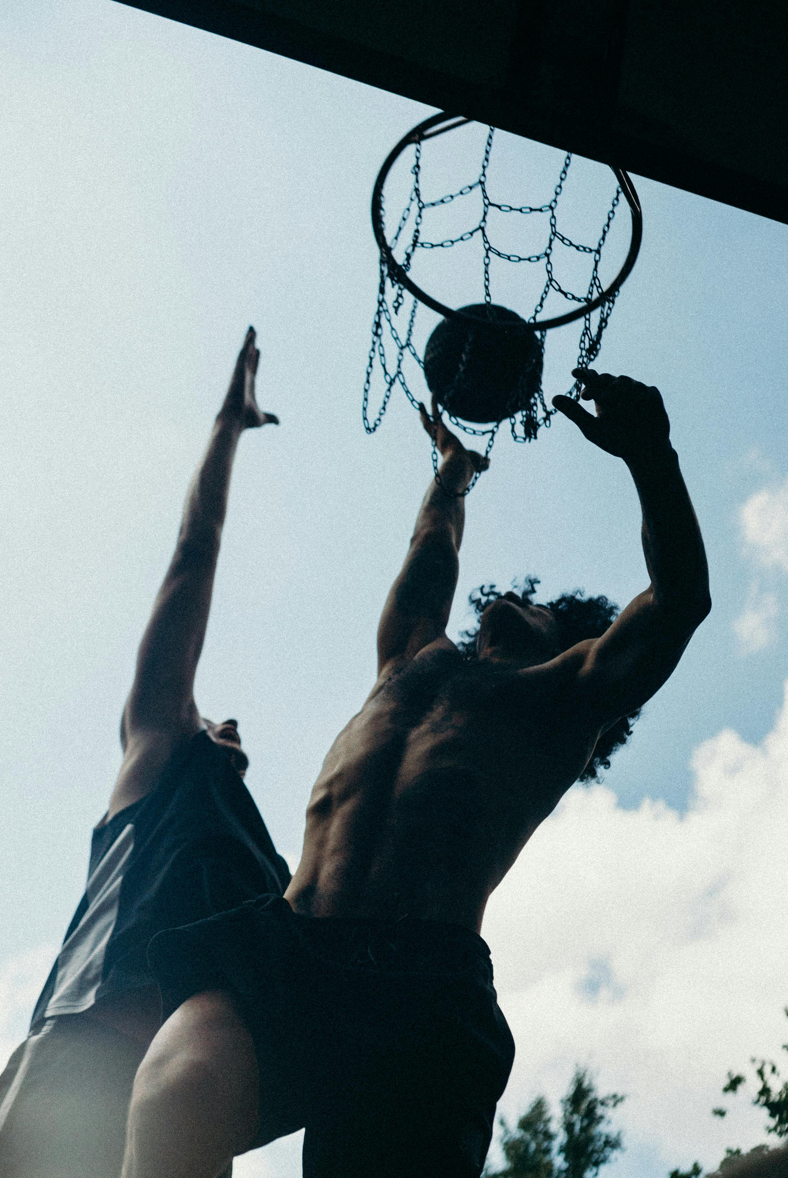 man in black shorts hanging on basketball hoop