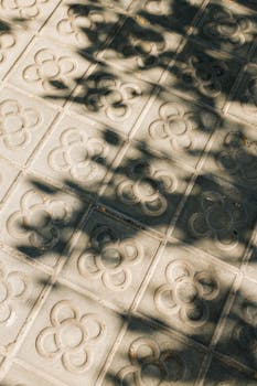 Decorative concrete tiles with shadows on a Barcelona sidewalk.