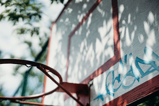 An artistic close-up of a basketball hoop and backboard with graffiti.