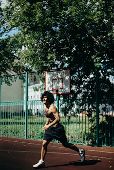 Shirtless man playing basketball outdoors on a sunny day, showcasing athleticism and vitality.