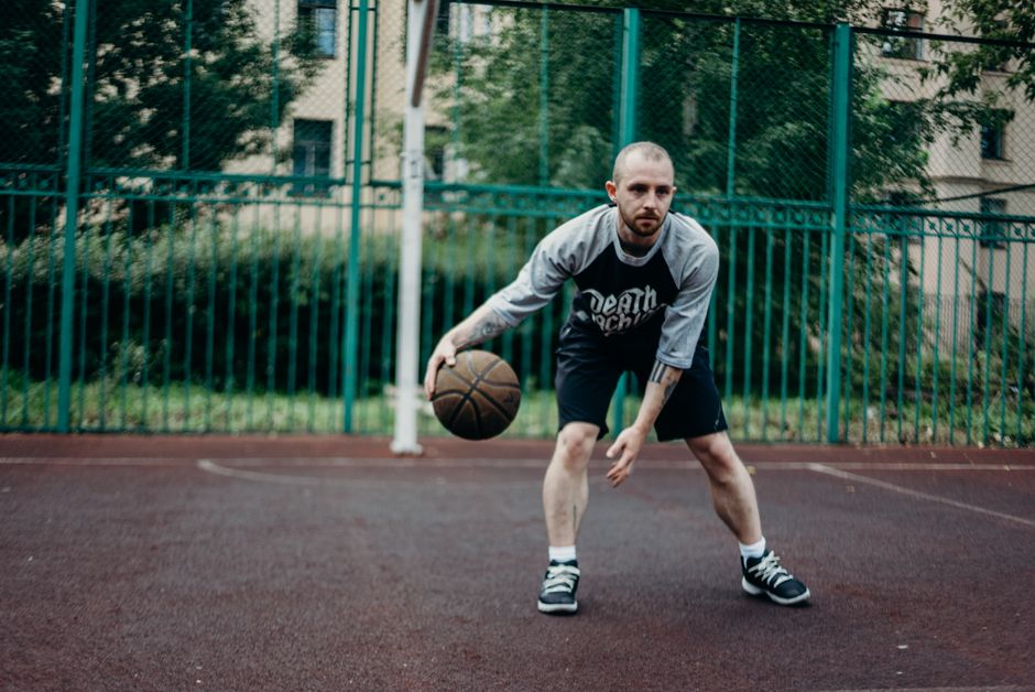 A man dribbling a basketball on an outdoor court surrounded by greenery. A man dribbling a basketball on an outdoor court surrounded by greenery.