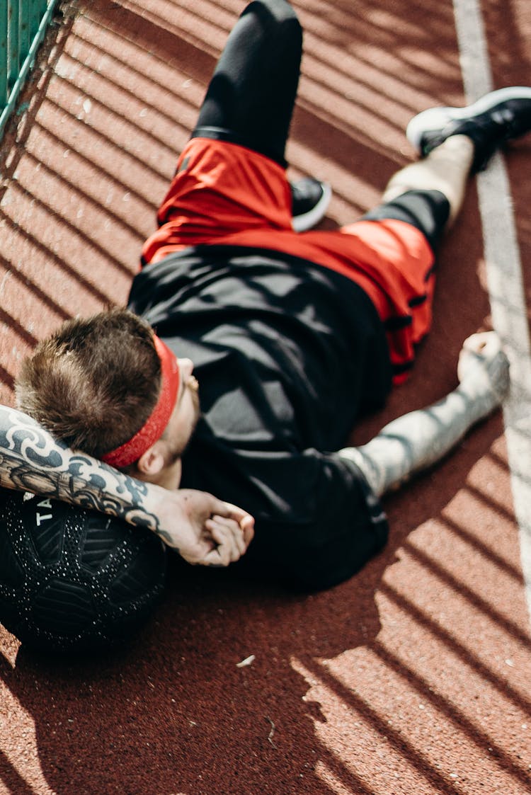 A Man Lying Down On A Basketball