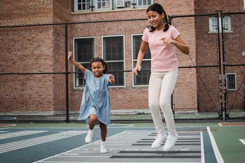 Free 2 Women in Blue Polo Shirt and White Pants Running on Track Field Stock Photo