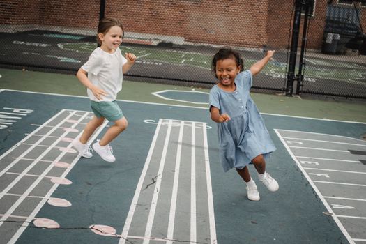 Two happy children playing and running on a musical-themed outdoor court with laughter and excitement.
