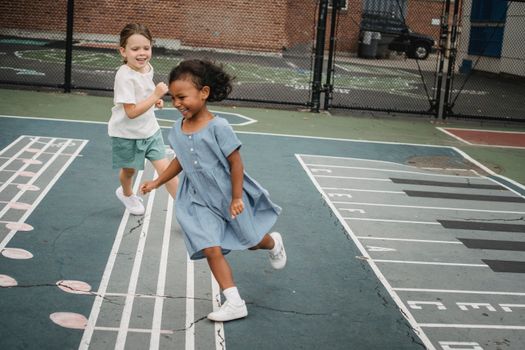 Two children happily playing and running on a music-themed playground in daylight.
