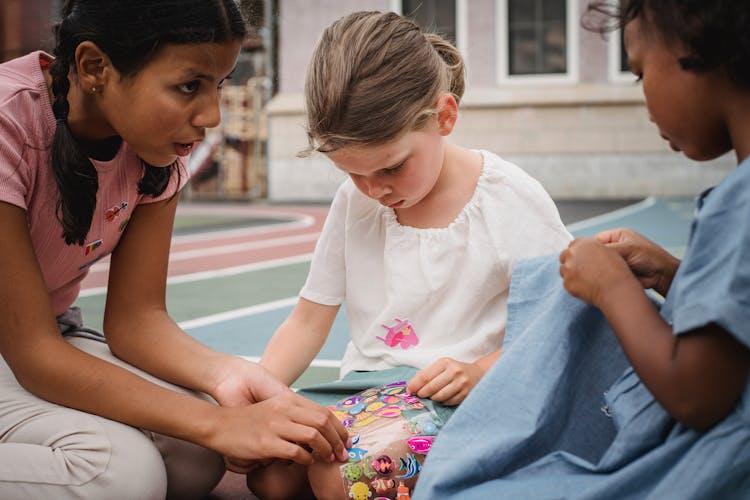 Small Children Playing With Stickers Outdoors