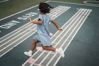 Girl in Blue Dress Walking on Gray Asphalt Road