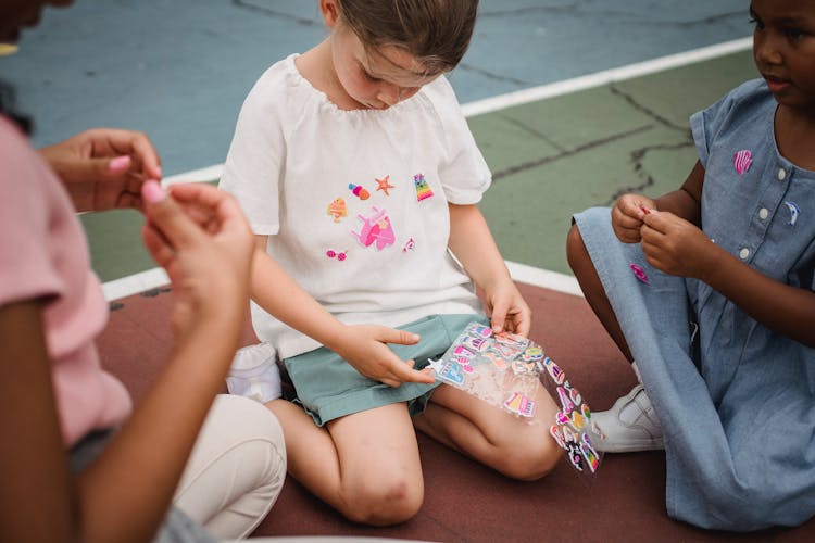 Small Girls Decorating Clothes With Stickers