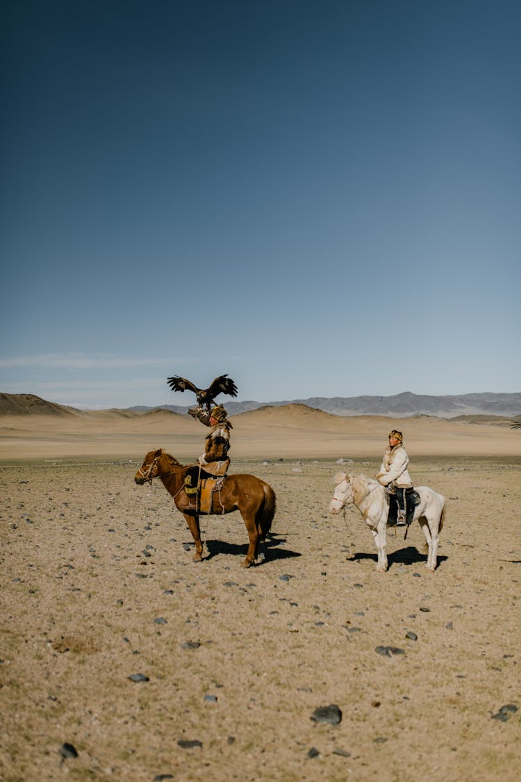 Ethnic People Riding Horses In Desert