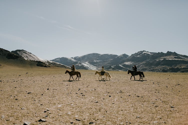 People On Horses In Desert Against Mountains