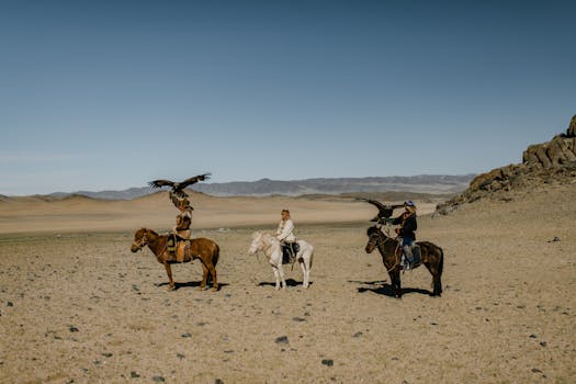 Traditional Mongolian eagle hunters on horseback in the vast desert landscape.