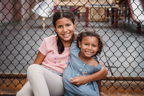Girl in Pink Shirt Sitting Beside Girl in Blue Shirt