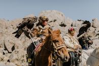 Mongolian horsemen with eagles riding on rocky terrain