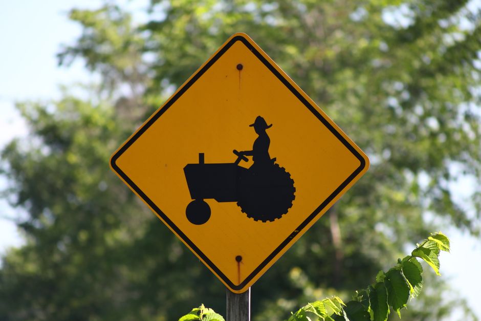 Diamond-shaped yellow caution sign featuring a tractor silhouette, a common example of safety signs for farms. Diamond-shaped yellow caution sign featuring a tractor silhouette, a common example of safety signs for farms.