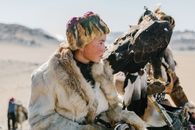 A Kazakh eagle hunter in traditional fur clothing, training a golden eagle in Mongolia's vast steppe.