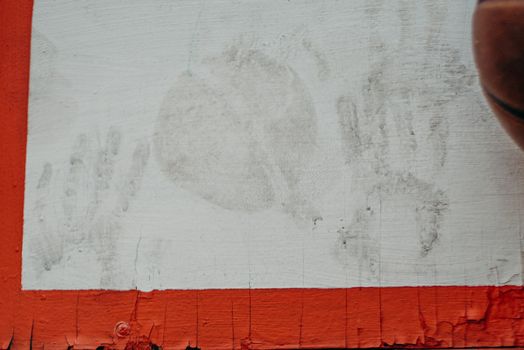Close-up of dusty handprints and basketball on a weathered backboard.
