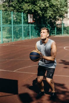 Adult man practicing basketball outdoors on a sunny day.