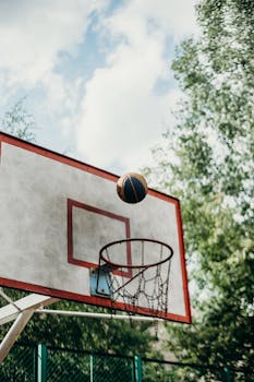 Basketball hoop and ball outdoors against a clear sky, perfect for sports themes.
