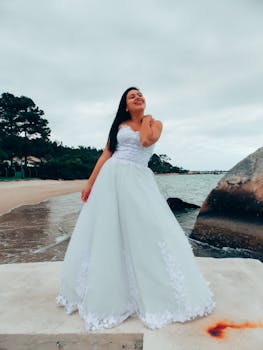 Bride in beautiful wedding dress poses by the serene beach, capturing a perfect wedding moment.