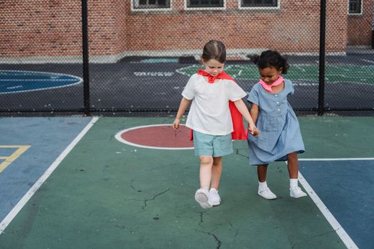 Two young girls enjoy a playful moment on a colorful urban playground.