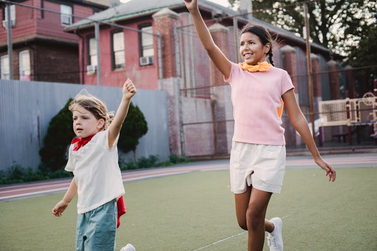 Happy Girls Playing Superheroes On Street