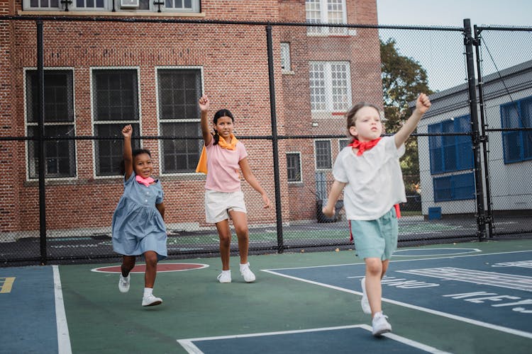 Little Girls Playing Superheros Outdoors On A Court In City 