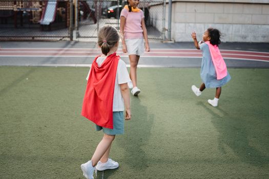 Three children enjoy playtime and imagination on an outdoor playground.
