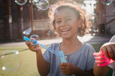 A child laughing while blowing soap bubbles, photo by Antonius Ferret on Pexels