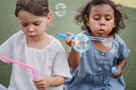 Girl in Blue Button Up Shirt Blowing Bubbles