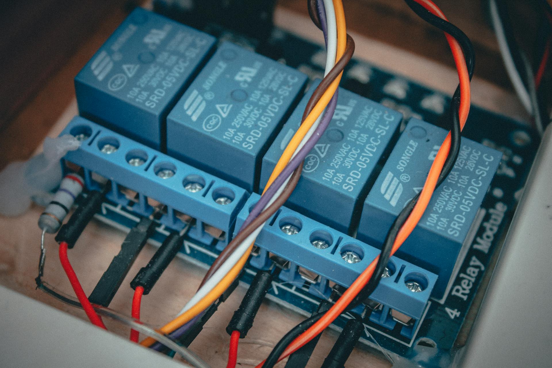 Blue relay modules with colorful wires connected on an electronic board.