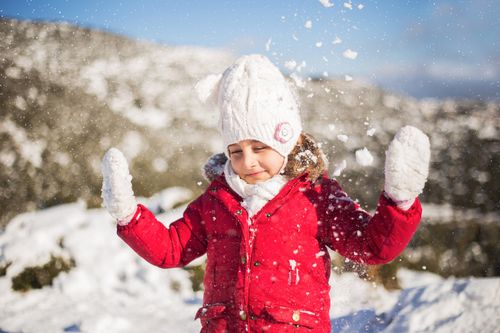 Free Young girl in winter attire joyfully playing in the snow, capturing the essence of winter fun. Stock Photo