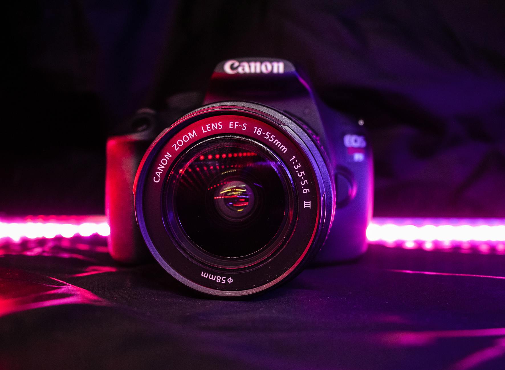 Front view of DSLR camera with reflective lens and purple LED lights in the background.