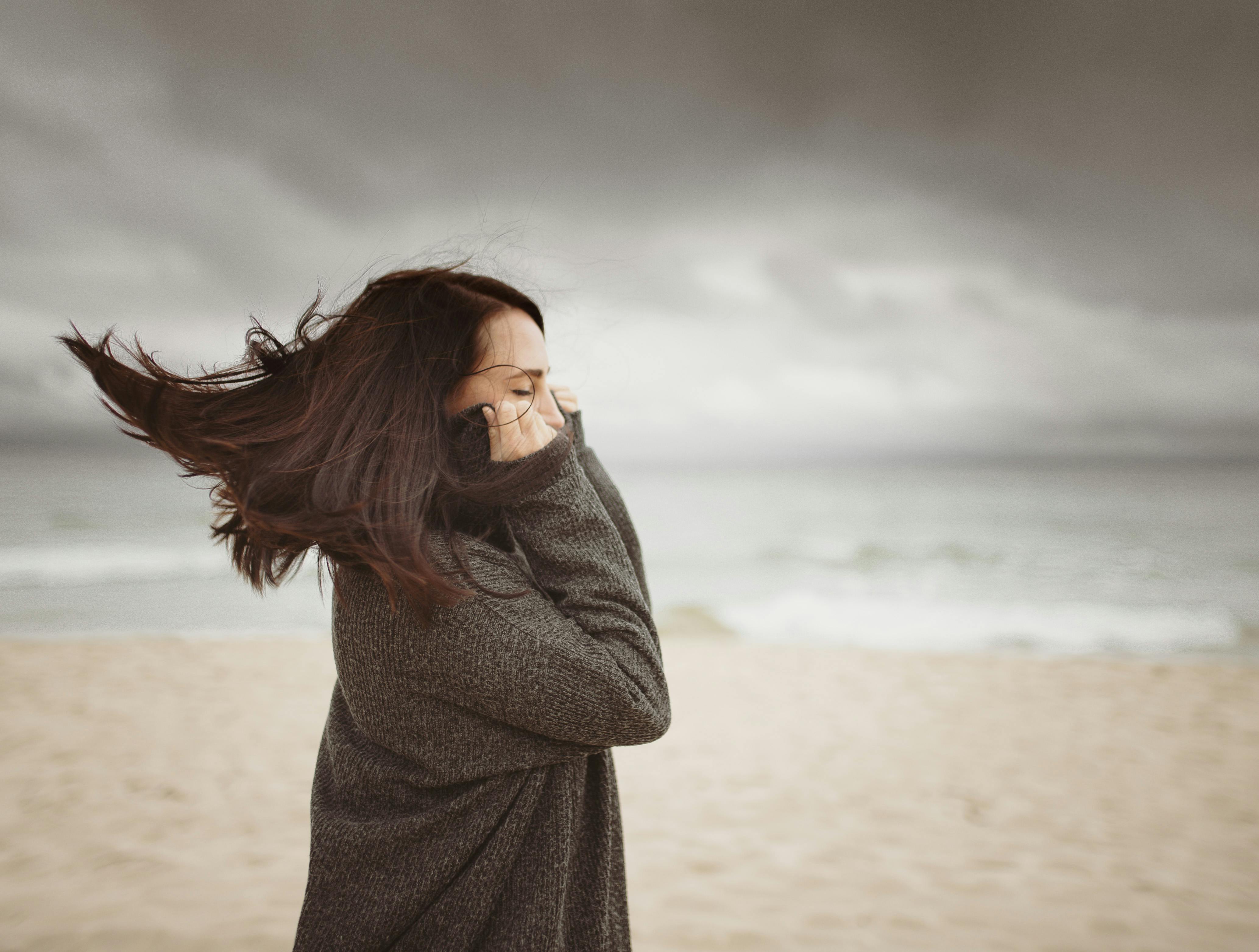 Dreamy young woman with windy hair recreating on seashore against ...