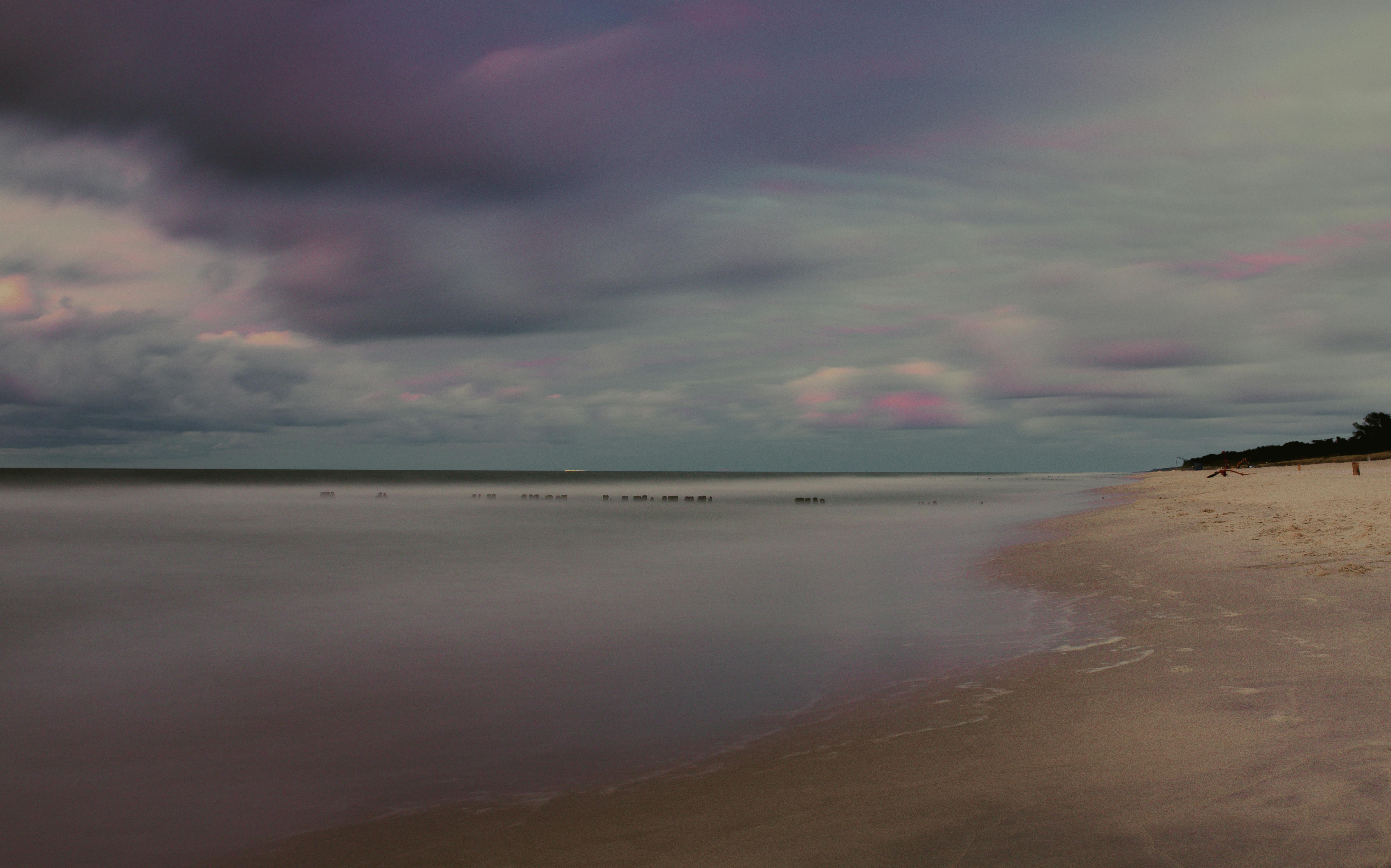 Sandy coastline of ocean against cloudy sundown sky \u00b7 Free Stock Photo