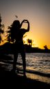 Silhouette of Woman Standing on Beach during Sunset