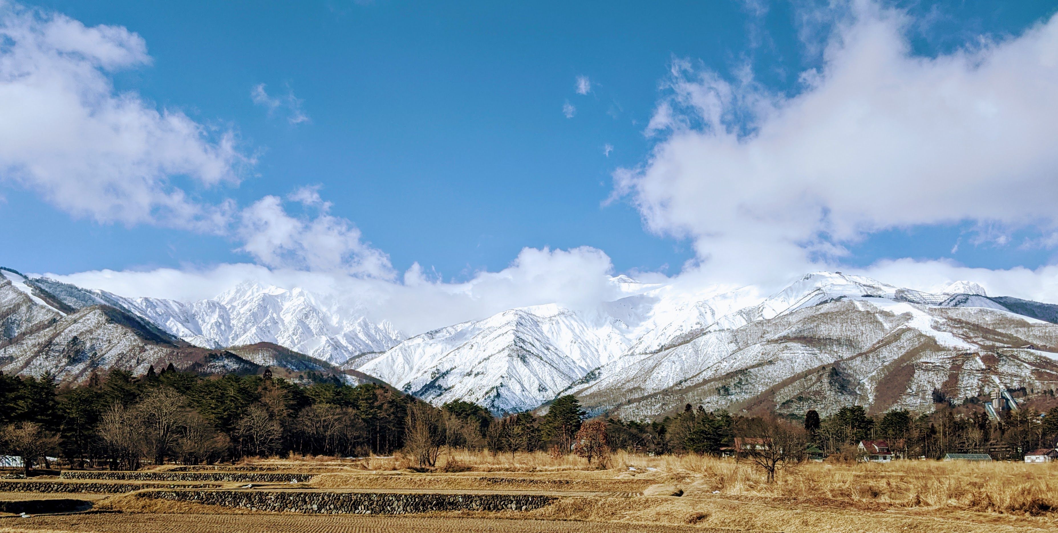 Breathtaking view of snow-capped mountains under a blue sky in Hakuba, Japan.