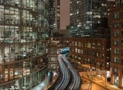 夜晚的城市景观充满活力，灯火通明的建筑与在曲线轨道上驶过的火车交相辉映