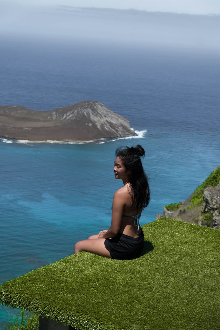 Peaceful Young Ethnic Woman Sitting On Edge Of Beach House Against Picturesque Sky