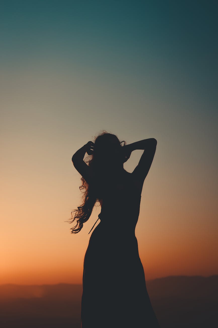 Silhouette of Woman Raising Her Hands during Sunset · Free Stock Photo
