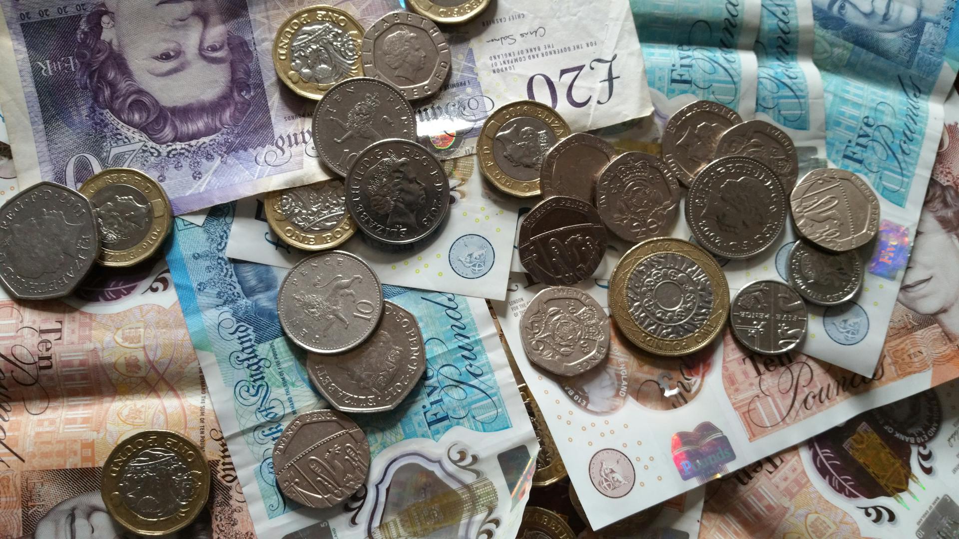 Close-up of British coins and banknotes, showcasing different denominations for financial concepts.