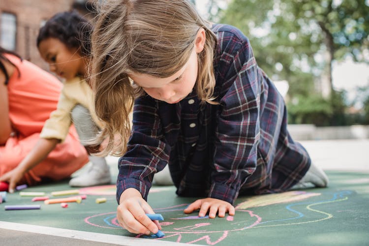 Children Drawing With Chalk On Asphalt