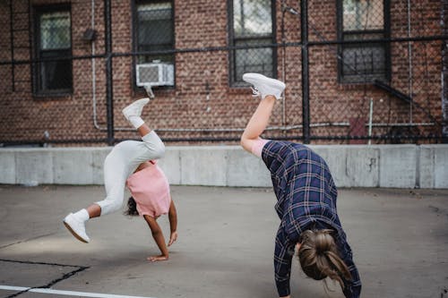 Girls Doing Cartwheels Outdoors on a Court in City 